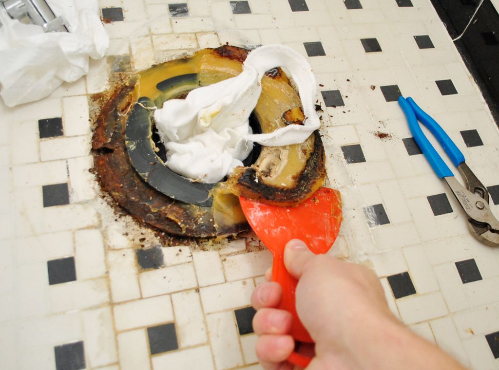 Scraping Old Wax Ring From Bathroom Floor During Toilet Installation