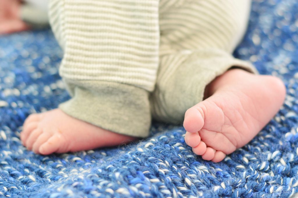 Small Newborn Baby Boy Feet On Blue Crochet Blanket