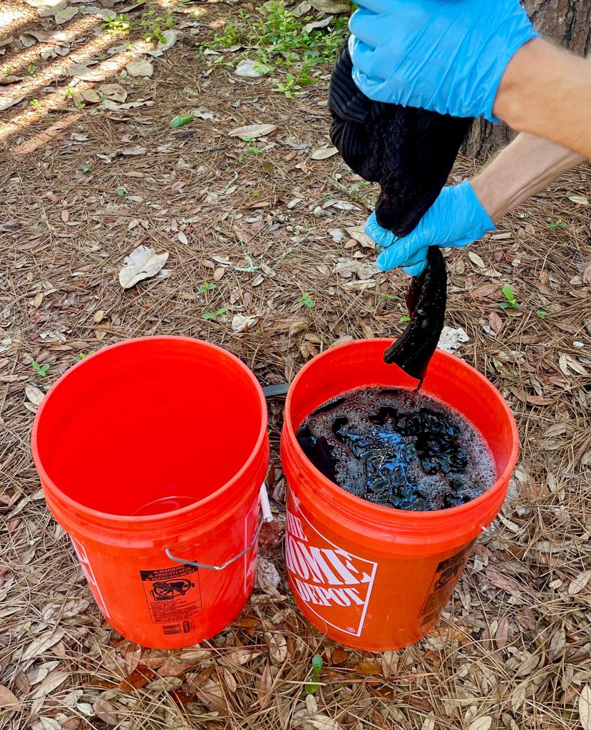 Squeezing Out Excess Fabric Dye From Black Sweater Over Bucket