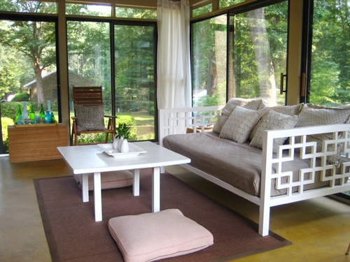 glass doored sunroom with golden yellow stained concrete floors and white daybed and coffee table